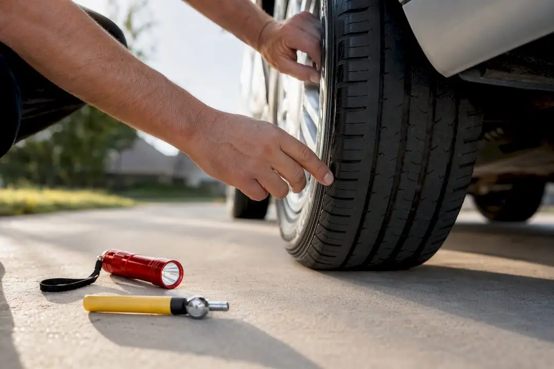 Driver checking tire before road trip