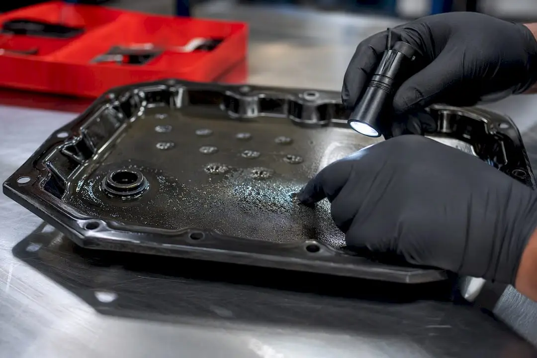 Technician examining metallic CVT pan debris